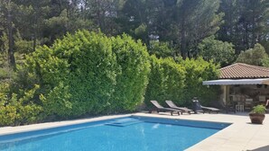 A rectangular swimming pool with clear blue water, surrounded by a tiled deck. There are lounge chairs and a small table near the pool. - Amazing home in Nebian (Nebian)