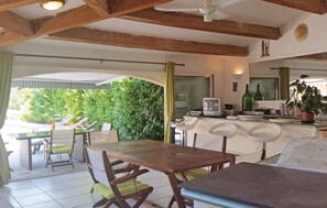 Un espace repas avec des tables et des chaises en bois, un téléviseur et un mur végétal.
