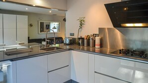 A modern kitchen with a stainless steel range hood, a built-in sink, and a toaster. - Amazing home in Nebian (Nebian)