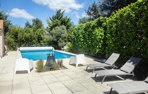 Une piscine avec des chaises longues et un espace patio.