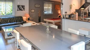 A modern kitchen with a central island, a dining area with a pool table, and a living room with a sofa and blinds. - Amazing home in Nebian (Nebian)