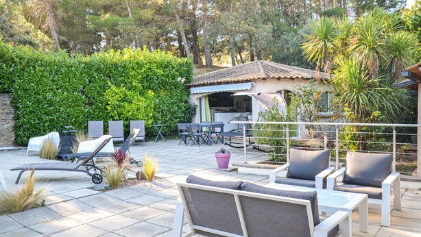 An outdoor patio with white furniture, a covered barbecue area, and a stone wall. - Amazing home in Nebian (Nebian)