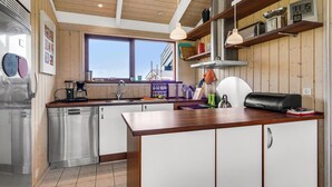 Une cuisine moderne avec des meubles en bois, des appareils en acier inoxydable et une grande fenêtre qui laisse entrer la lumière naturelle.
