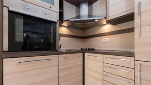 Una cocina moderna con armarios de madera, horno integrado y campana extractora.