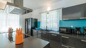 Een moderne keuken met roestvrijstalen apparatuur, een zwarte koelkast, een magnetron en een koffiezetapparaat.