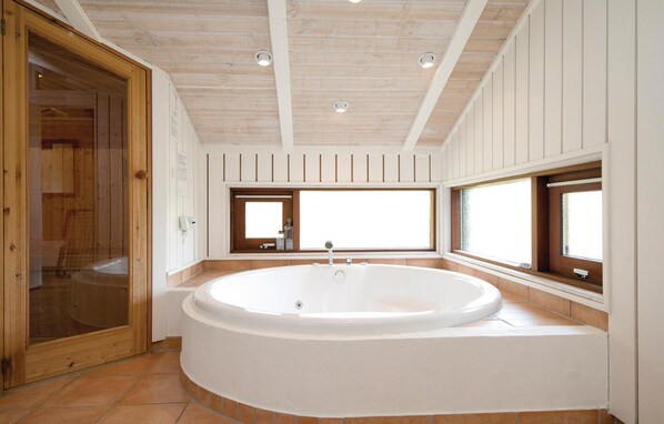 A modern bathroom with a freestanding bathtub, wooden panel walls, and large windows. - Gorgeous home in ålbæk with sauna (Ålbæk)