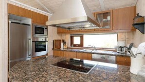 A modern kitchen with granite countertops, stainless steel appliances, and wooden cabinetry. - Gorgeous home in ålbæk with sauna (Ålbæk)