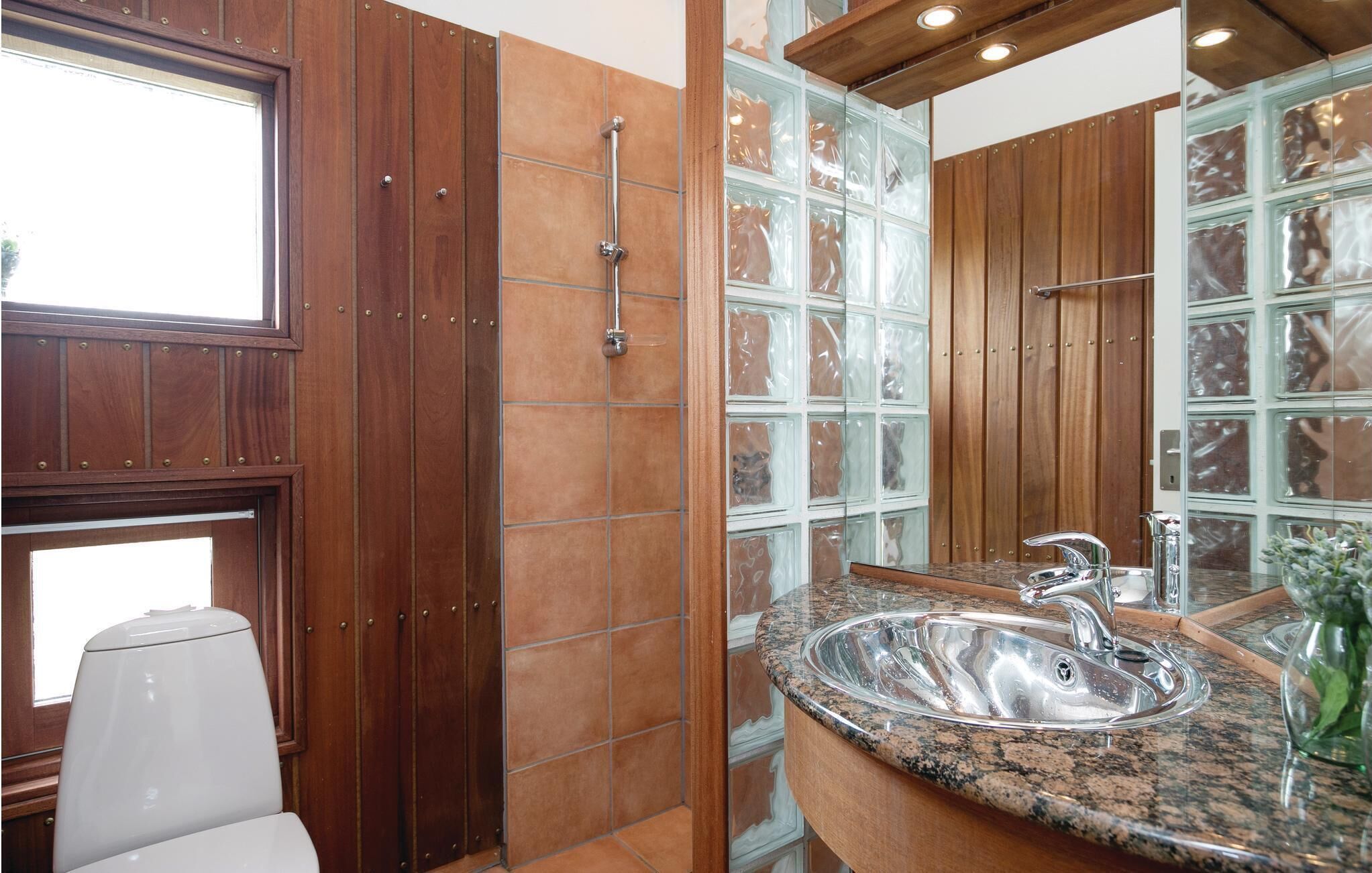 A bathroom with wooden cabinets, a glass shower enclosure, and a granite countertop with a sink.