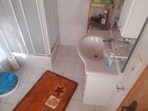 A bathroom with a sink, toilet, shower, and a blue toilet seat. - Triple - House Bamberger (Fischbachau)