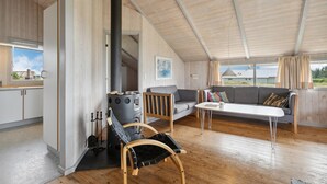 A cozy room with a wooden ceiling, a sofa, a small table, and a chair.