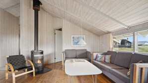 A cozy living room with a wood-burning stove, a sofa, a table, and a bench.