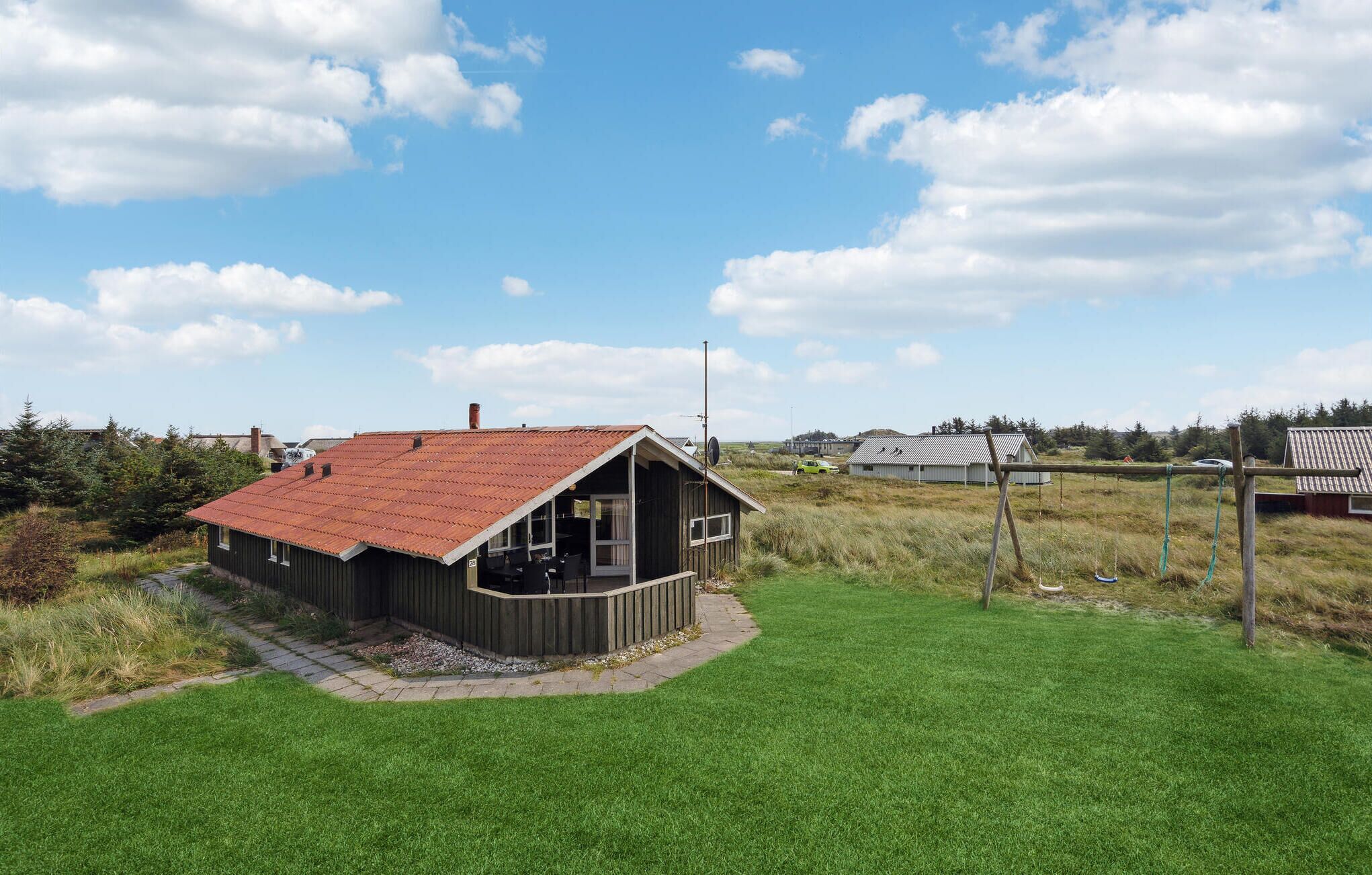 A wooden cabin with a red roof, a small porch, and a satellite dish.