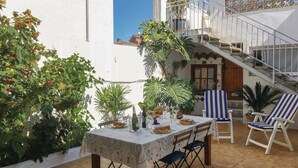 Un patio con tavolo apparecchiato per mangiare, circondato da piante in vaso e mobili da giardino.