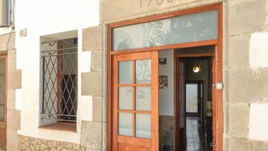 Un edificio con facciata in pietra, una porta in legno con vetri e una finestra con inferriate.