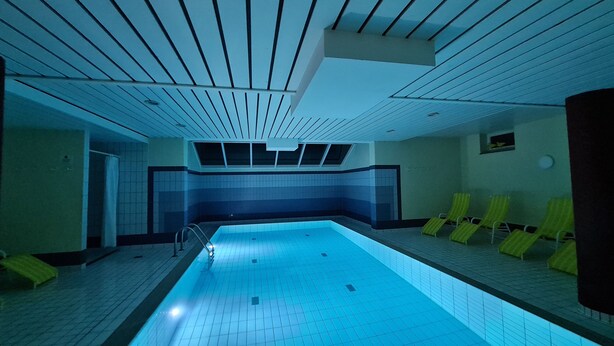 An indoor swimming pool with a tiled floor and walls, a skylight, and yellow lounge chairs along the side. - Villa a cappella A2 - Villa a cappella (Binz)