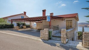 Una casa de dos pisos con un camino cubierto y un portón de piedra.