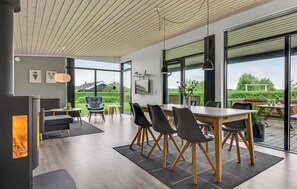 A modern dining area with a large table, chairs, and a fireplace. - Beach front home in Sydals with sauna (Sydals)