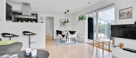 A modern living room with a dining area, a kitchen, and a TV.