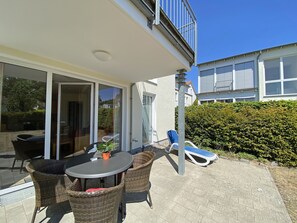 Une terrasse extérieure avec des meubles en osier, une table et une plante en pot.