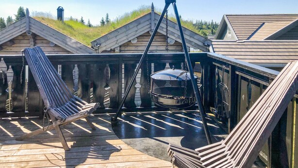 Eine Holzterrasse mit Grill, hängendem Topf und einem Stuhl.