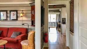 Ein gemütliches Zimmer mit einem roten Sofa, einem hölzernen Hocker und einem gerahmten Kunstwerk an der Wand.