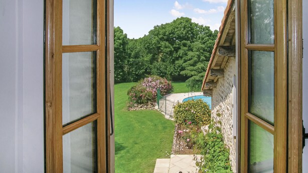 An open door revealing a garden with a swimming pool, stone wall, and lush greenery. - Awesome home in Souvigne (Souvigne)