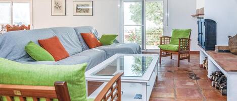 Ein gemütliches Wohnzimmer mit einer Couch, Sesseln, einem Glastisch und einem Fernseher.