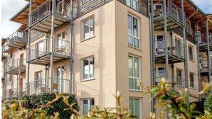Un edificio residencial de varios pisos con balcones, ventanas amplias y cielo despejado.