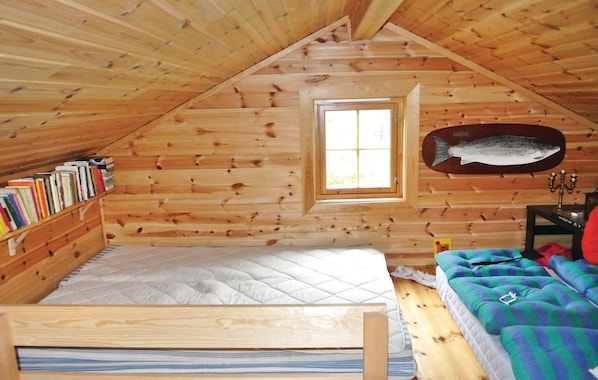 A cozy attic bedroom with a sloped ceiling, a small window, a bed, a bookshelf, and a decorative fish on the wall. - Cozy home in Rendalen with sauna (Rendalen)
