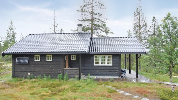 Une petite cabane en bois avec un toit en tuiles, une véranda et un panneau solaire.