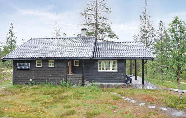 Une petite cabane en bois avec un toit en tuiles, une véranda et un panneau solaire.