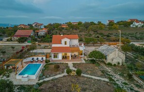 Ein zweistöckiges Haus mit Swimmingpool, einer Terrasse und Gartenmöbeln sowie einer Steinstruktur.