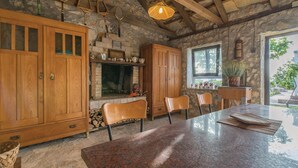 Une cuisine rustique avec des meubles en bois, une cheminée en pierre et une table à manger entourée de chaises.