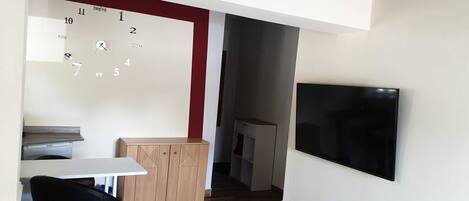 Una cocina moderna con un mueble de madera, una encimera blanca y una silla negra.