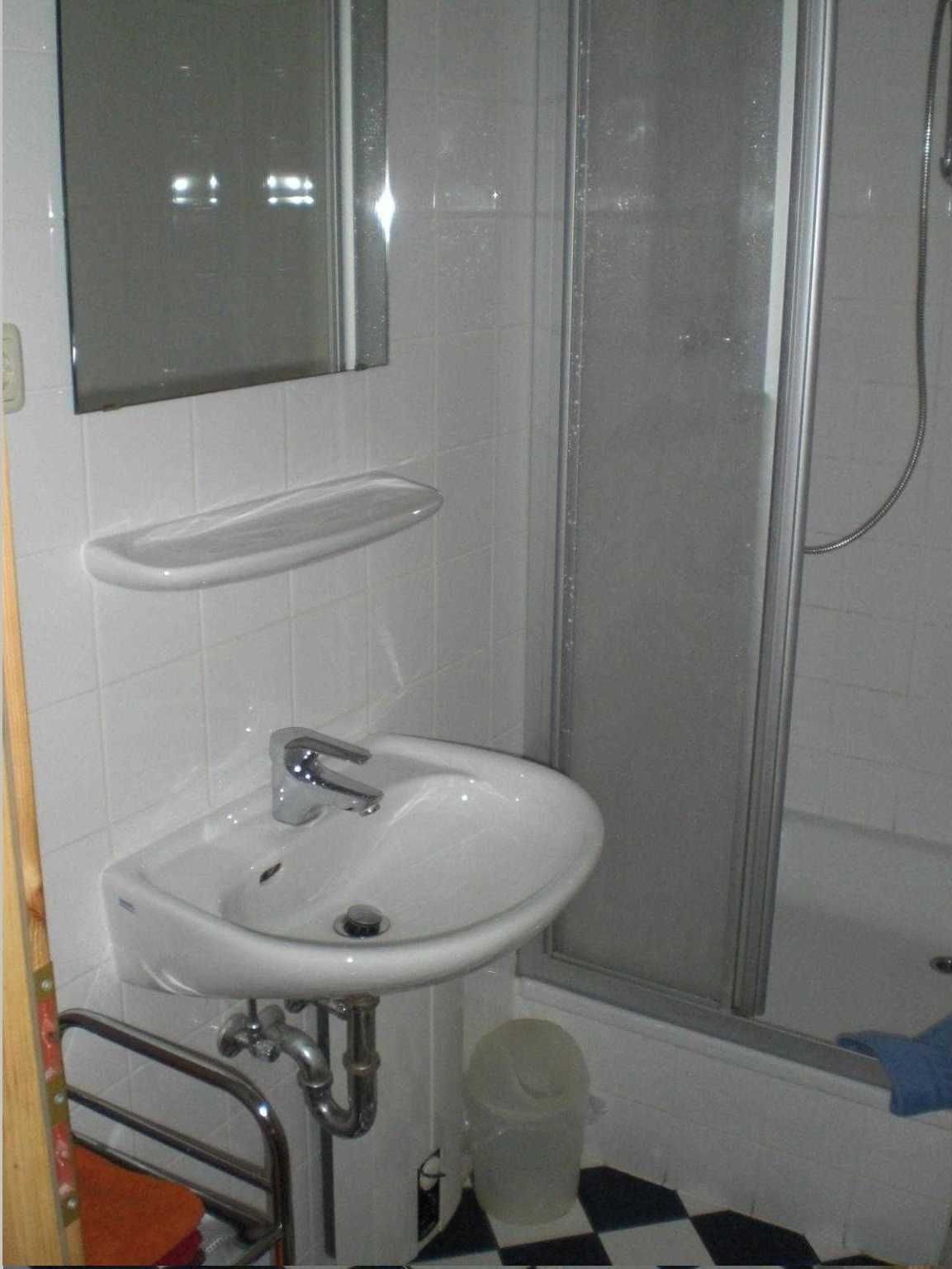 A bathroom with a white sink, a mirror, and a shower enclosure.