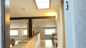 A room with a sloped ceiling, a skylight, and a wooden bench.