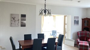 A dining area with a wooden table and chairs, a chandelier, and artwork on the walls.