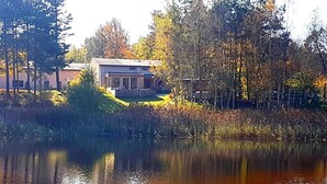 A house with a deck, surrounded by trees and a body of water.