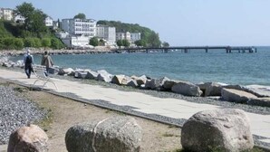A coastal walkway with large rocks, a pier, and buildings in the background. - Apartment 6 - Sassnitz - Apartments in bath villa with Baltic Sea view (Sassnitz)