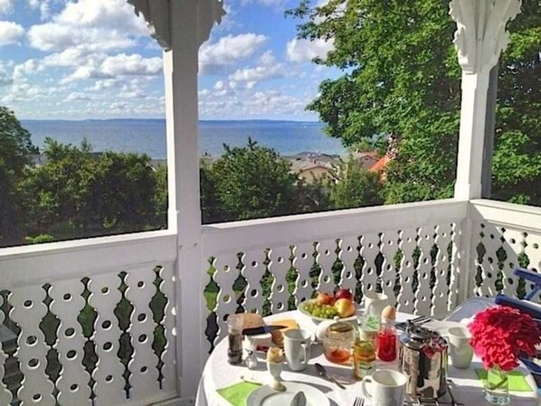 A table set for breakfast with a view of the sea and greenery.