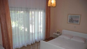 Quarto com cama, mesa de cabeceira e abajur.