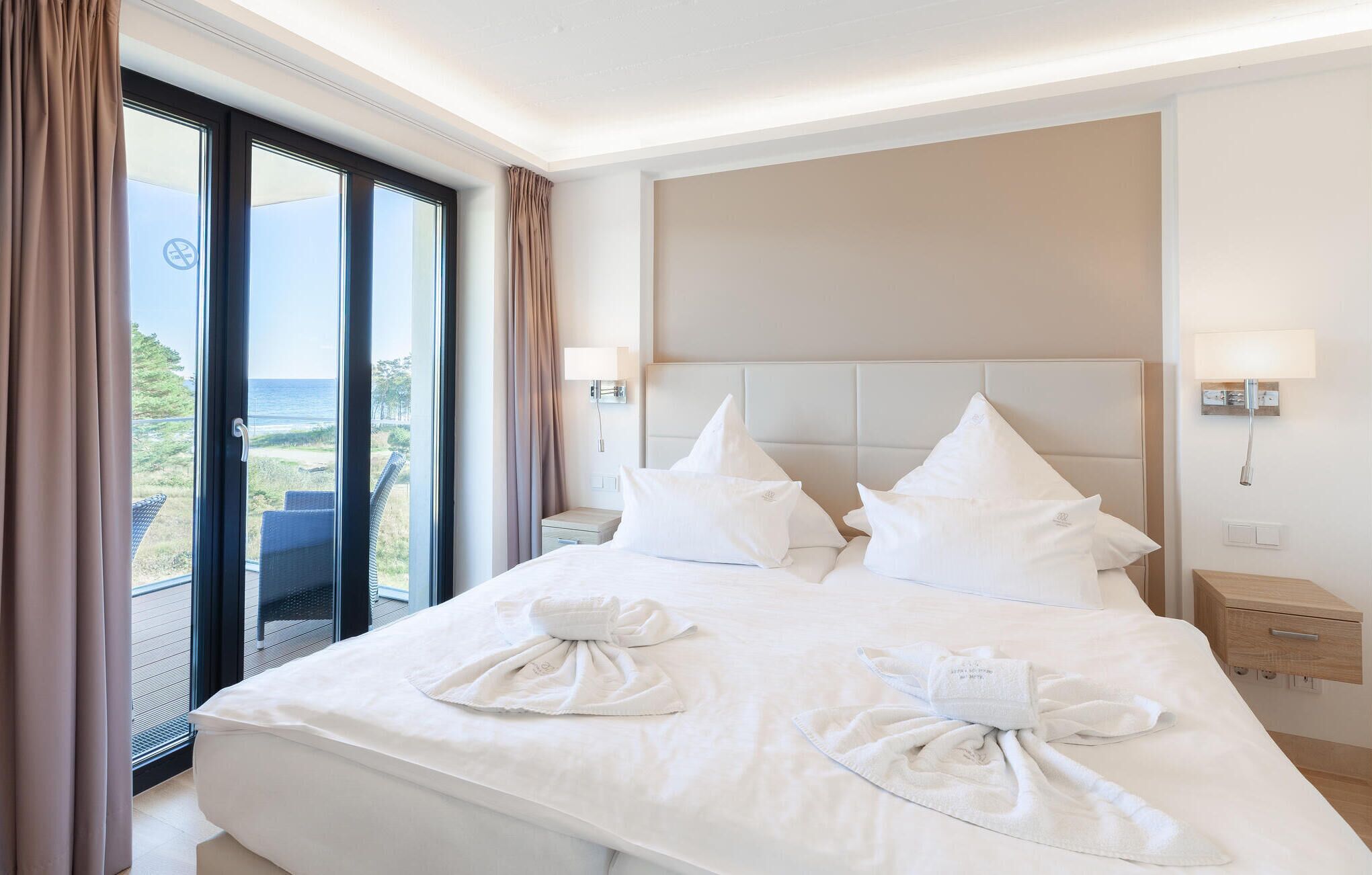 Une chambre d’hôtel avec un grand lit, deux tables de chevet, une tête de lit et une vue sur la mer.