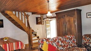 A wooden staircase, a sofa with floral upholstery, and a table with a striped tablecloth. - 2 bedroom awesome home in Garlan (Garlan)