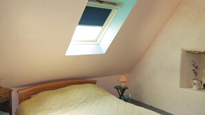 A bedroom with a skylight, a bed, a nightstand, a lamp, and a shelf with a vase. - 2 bedroom awesome home in Garlan (Garlan)