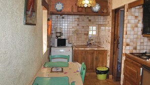 A compact kitchen with a microwave, sink, and wooden cabinets. - 2 bedroom awesome home in Garlan (Garlan)
