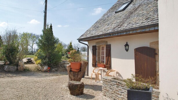 A rustic house with a gravel driveway, wooden furniture, and potted plants. - 2 bedroom awesome home in Garlan (Garlan)