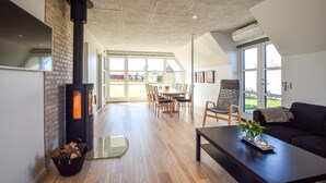 Un salon moderne doté d’une cheminée, de planchers en bois et d’un coin repas baigné de lumière naturelle.