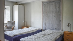 A bedroom with two beds, a wooden nightstand, a chair, and a wardrobe. - Gorgeous home in Tomelilla with WiFi (Tomelilla)