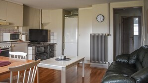 A compact kitchen with a refrigerator, microwave, and stove. There is a dining table with chairs and a black leather couch in the living area. - Gorgeous home in Tomelilla with WiFi (Tomelilla)