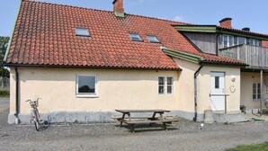 A two-story house with a red-tiled roof, a wooden balcony, and a picnic table in front. - Gorgeous home in Tomelilla with WiFi (Tomelilla)